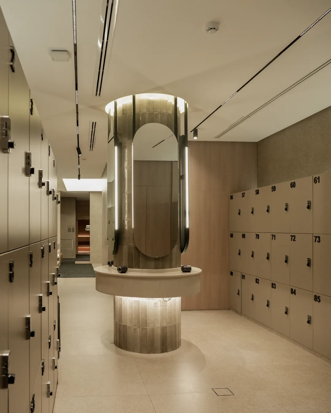 The changing room at Vy Boutique — numbered lockers and a backlit oval mirror pillar