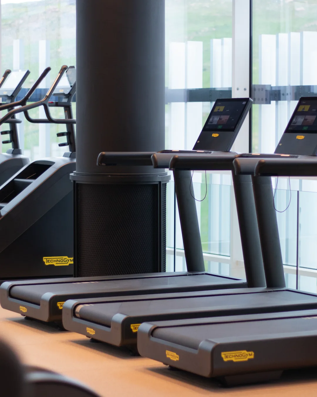 A row of treadmills facing the windows on the cardio floor at Vy Boutique